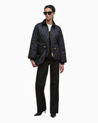 Styled outfit shot with quilted jacket layered over knit jumper and trousers