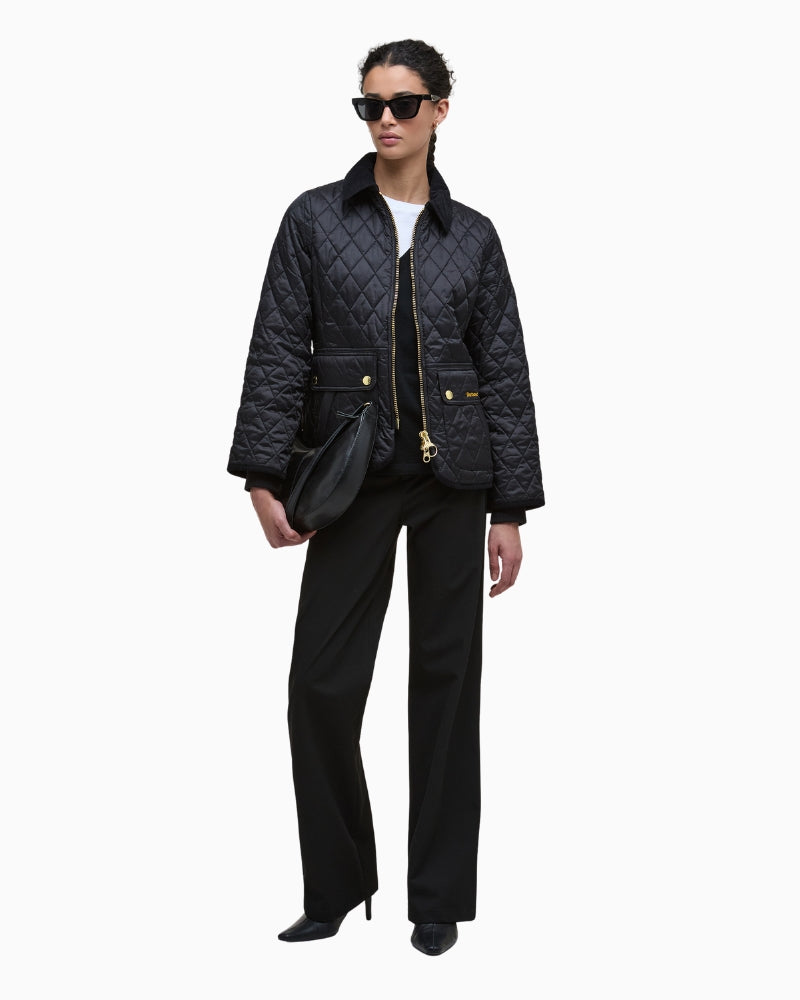 Styled outfit shot with quilted jacket layered over knit jumper and trousers
