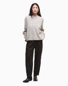 Model wearing beige jumper with relaxed black trousers