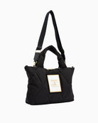Angled view of Barbour quilted mini tote in black with shoulder strap positioned upward