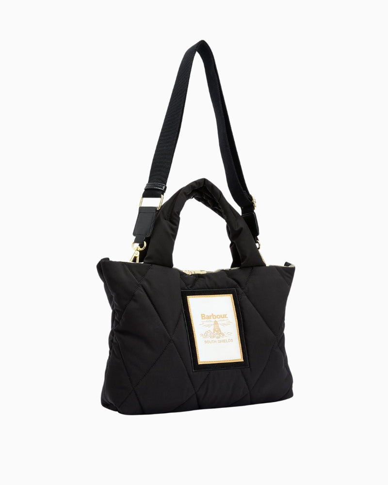 Angled view of Barbour quilted mini tote in black with shoulder strap positioned upward