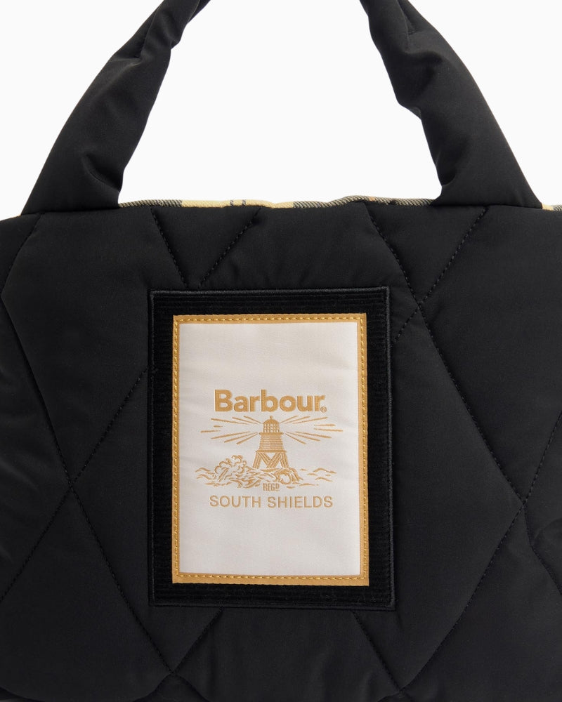 Close-up of Barbour beacon-inspired patch logo on quilted black tote bag fabric