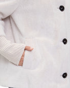 Close-up of piped pocket and plush fabric on women’s short jacket