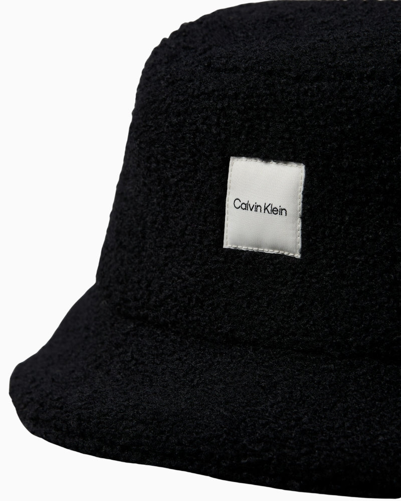 Close-up of Calvin Klein logo patch on textured black hat