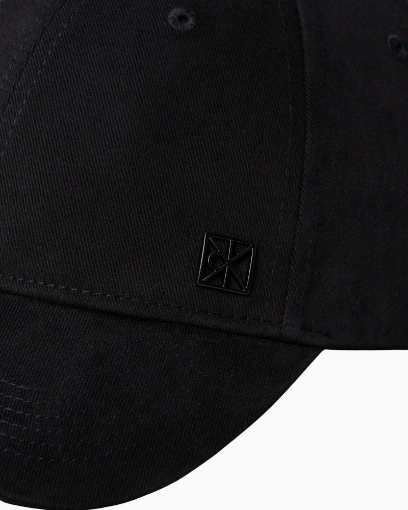 Close-up of Calvin Klein emblem detail on front of cap

