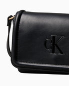 Close-up of embossed CK monogram on soft black faux leather