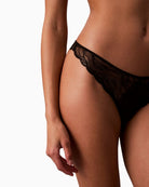 Side view of Calvin Klein lace thong with scalloped trim, cut-out back, and logo detail