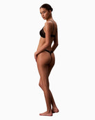 Side view of Calvin Klein lace thong with scalloped trim, cut-out back, and logo detail