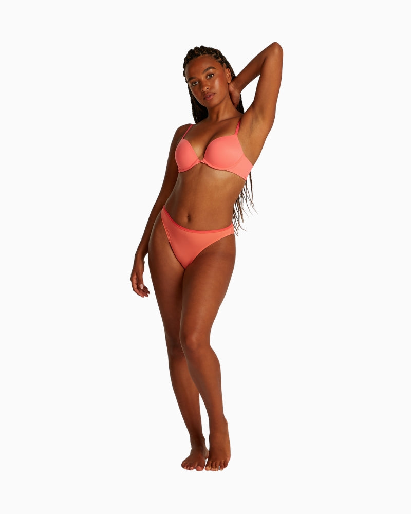 Full body view of model wearing Calvin Klein plunge bra and matching briefs
