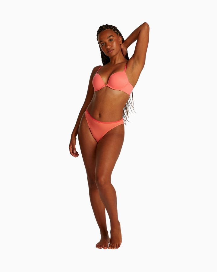 Full body view of model wearing Calvin Klein plunge bra and matching briefs