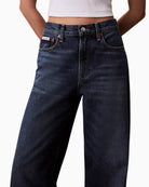 Close up view of Calvin Klein wide leg jeans in dark indigo denim with medium rise and full-length leg