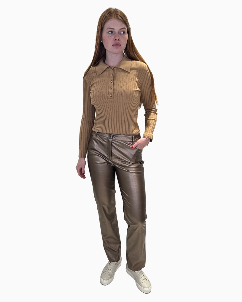 Full length view of a woman in the Eva Kayan ribbed polo jumper and metallic trousers.