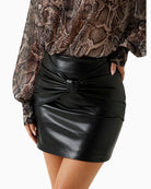 Front view of black gloss mini skirt with bow detail and fitted waist