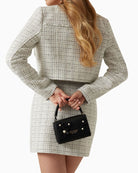 Front view of mini handbag with gold logo and flap closure