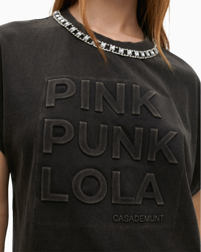 Close-up of neckline jewels and textured lettering detail on washed fabric
