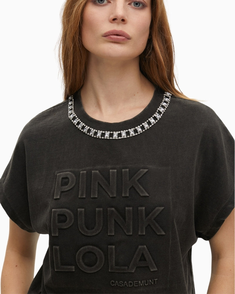 Close-up of neckline jewels and textured lettering detail on washed fabric