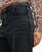 Close-up of high waist and metallic button closure on stretch denim