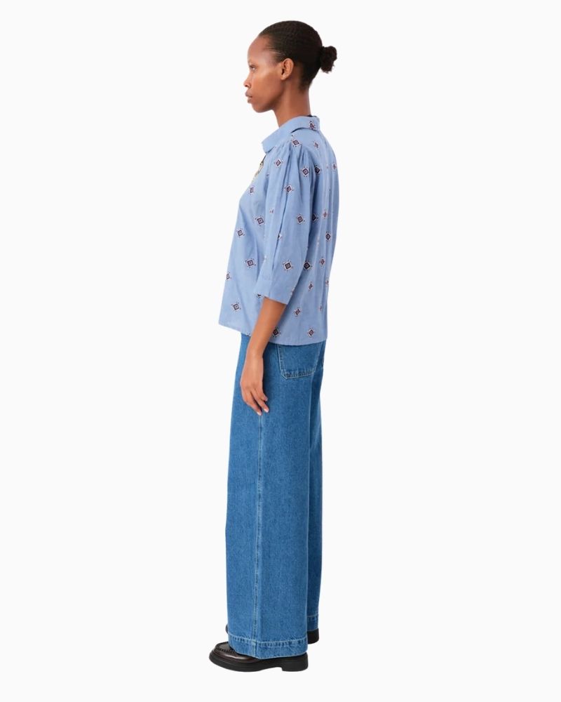 Side of blue cotton shirt with embroidered detail and ¾-length sleeves