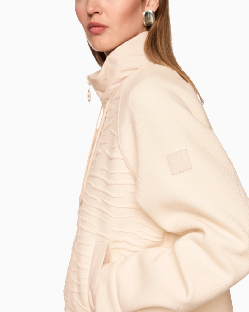 Close-up of mixed textures: ribbed sleeve, printed front panel