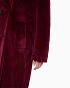 Close-up of button and pocket detail on soft maroon Marc Cain coat