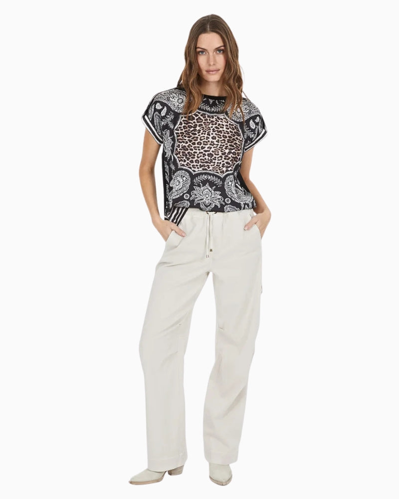 Model wearing Marc Aurel scarf print blouse with white trousers