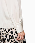 Close-up of patent button and rhinestone detail on Marc Cain silk shirt