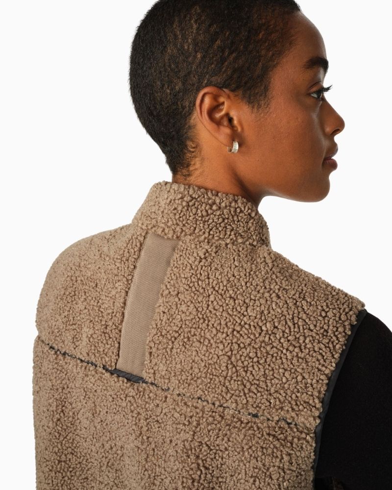 Close up view of Mos Mosh teddy waistcoat in cream with contrast piping, zip front, and graphic side slits