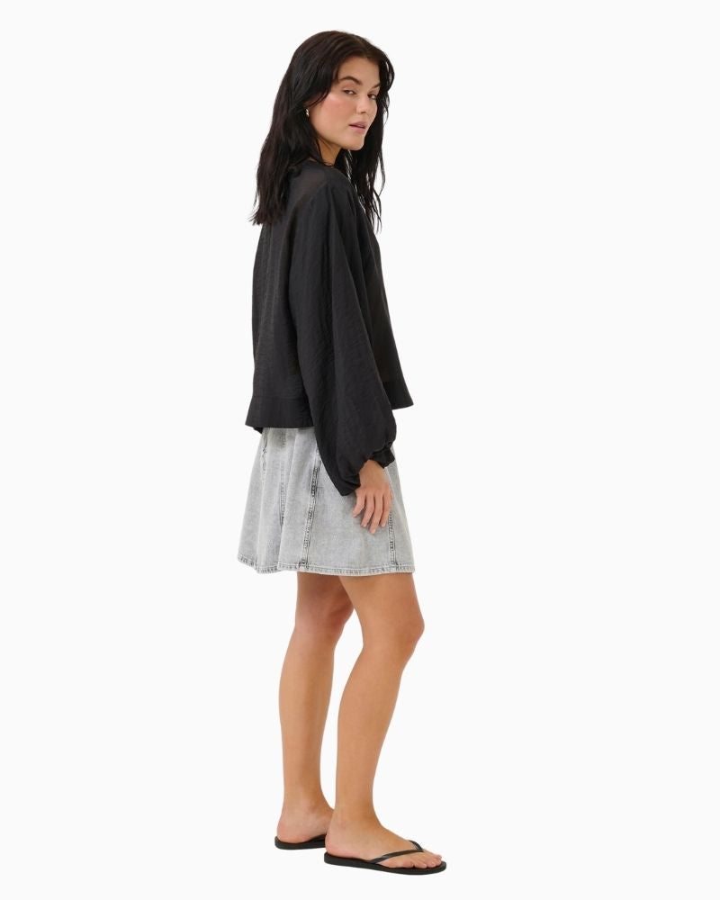 Side view of A-line blue denim mini skirt by My Essential Wardrobe with panel seams