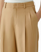 Close-up of waistband, pleats, and soft drape of twill fabric