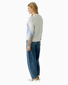 Side view of blue/white knit jumper styled with jeans