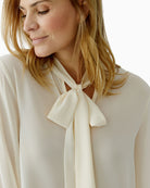 Close-up of elegant neckline with bow detail on off-white blouse