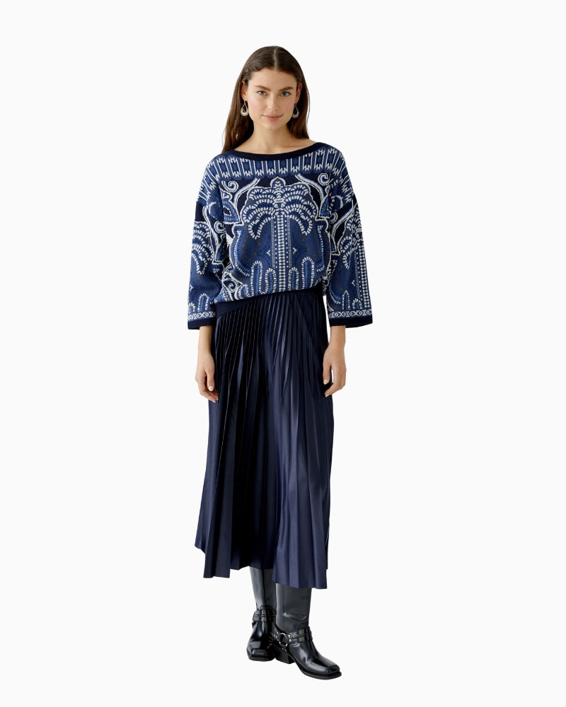 Model wearing Oui pullover styled with jeans and navy skirt