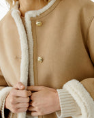 Close-up of gold crest button detail on camel faux leather jacket by Oui