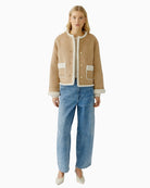 Model wearing camel faux leather jacket layered over knit and jeans