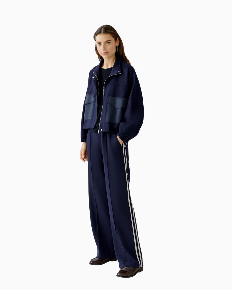 Model wearing trousers with trainers and knitwear