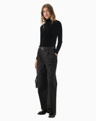 Model wearing black velvet top styled with high-waisted trousers