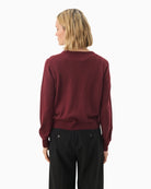 Back view of fine knit cardigan layered over neutral top