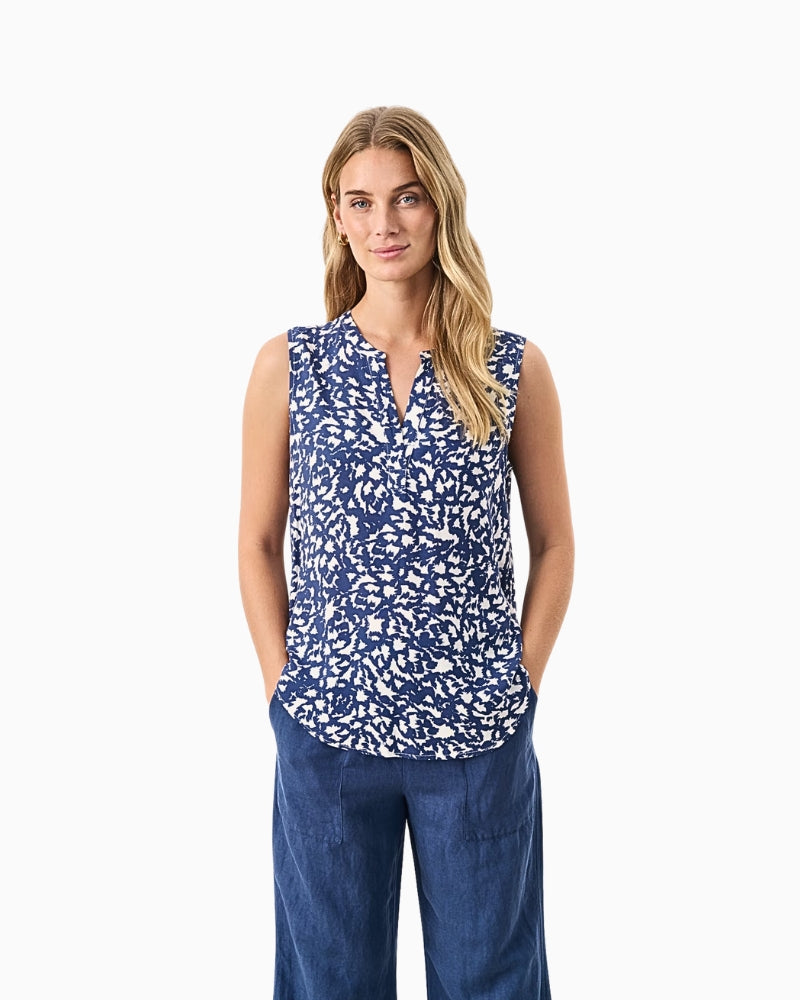 Model wearing sleeveless navy floral blouse with V-neckline, styled with wide-leg jeans