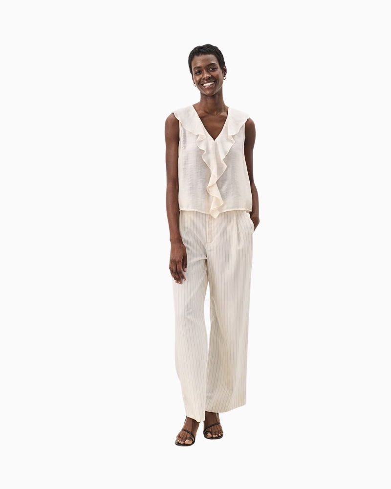 Ivory sleeveless ruffle blouse paired with matching wide-leg trousers for a chic summer co-ord look