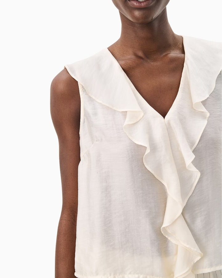 Close-up of ruffle-front sleeveless blouse in soft ivory with V-neckline