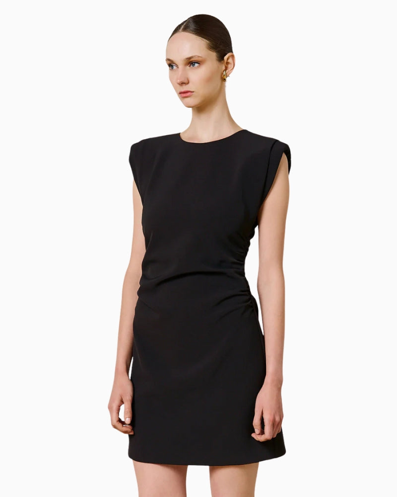 Woman wearing SPELL black mini dress, side view showing padded shoulders – Áines Boutique