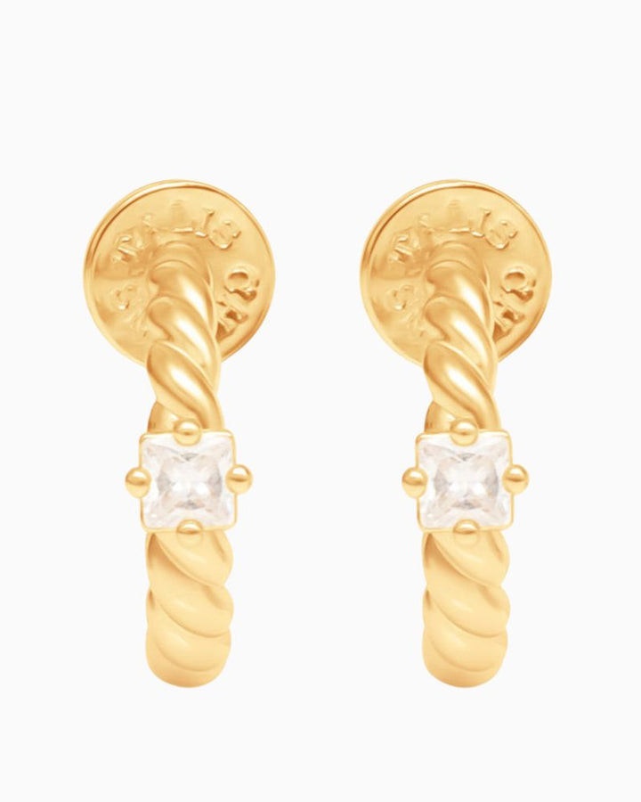 Close-up of twisted gold hoop earrings featuring small cubic zirconia stone