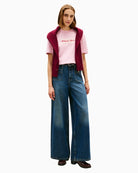 Model wearing pink tee tucked into jeans for casual look