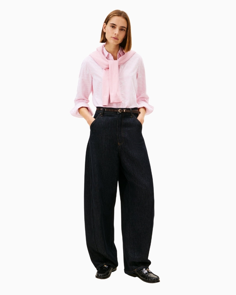 Model styling pink Oxford shirt with rolled sleeves and denim