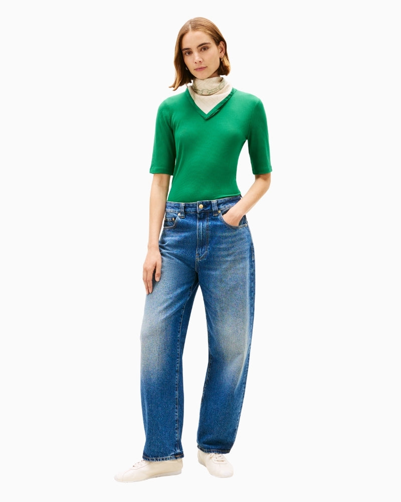Model wearing green ribbed tee tucked into jeans