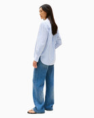 Back of Feminine blue shirt styled with white jeans for a fresh summer look

