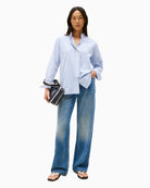 Feminine blue shirt styled with white jeans for a fresh summer look

