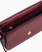 Side view of Tommy Hilfiger compact crossbody in structured red finish with flap closure