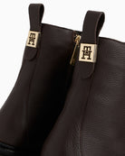Close-up of TH metal plaque on leather ankle boots by Tommy Hilfiger
