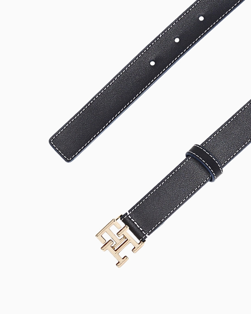 Close-up of Tommy Hilfiger belt showing adjustable strap and signature gold 'TH' buckle